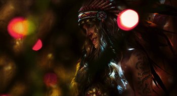 Movie still from “3 from Hell” (2019), directed by Rob Zombie – A woman in a headdress with lights in the background; Close Up shot, Over the shoulder angle