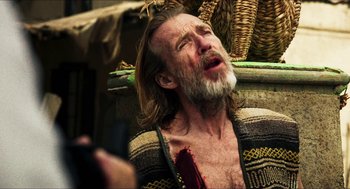 Movie still from “3 from Hell” (2019), directed by Rob Zombie – An old man with a beard and a mustache is sitting in a chair; Close Up shot, Over the shoulder angle