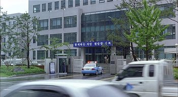 Movie still from “3-Iron” (2004), directed by Kim Ki-duk – A police car is parked in front of a building; Extreme Wide shot, Low angle