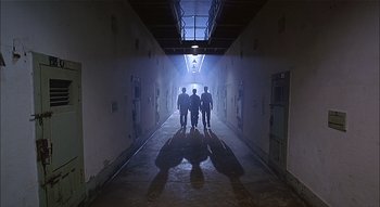 Three men are walking down a hallway in a building