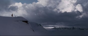 Movie still from “30 Days of Night” (2007), directed by David Slade – A person snowboarding down a mountain under a cloudy sky; Extreme Wide shot, Low angle