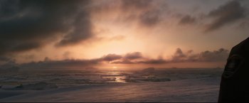 Movie still from “30 Days of Night” (2007), directed by David Slade – The sun is setting over the ocean on a cloudy day; Extreme Wide shot, High angle