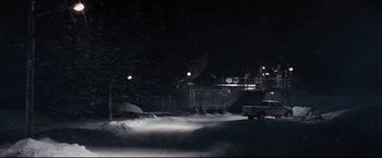 Movie still from “30 Days of Night” (2007), directed by David Slade – A dark picture of a snow covered area with lights; Extreme Wide shot, High angle