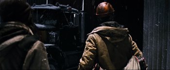 Movie still from “30 Days of Night” (2007), directed by David Slade – A man wearing a hard hat in a factory; Medium shot, Over the shoulder angle