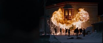 Movie still from “30 Days of Night” (2007), directed by David Slade – A group of people standing in front of a building with fire coming out of it; Extreme Wide shot, High angle
