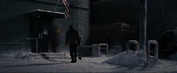 Movie still from “30 Days of Night” (2007), directed by David Slade – A person walking in the snow near a building; Extreme Wide shot, High angle