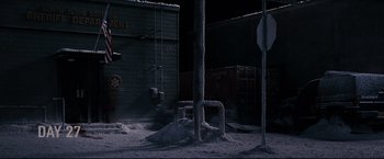 Movie still from “30 Days of Night” (2007), directed by David Slade – A pile of snow next to a street sign; Extreme Wide shot, High angle
