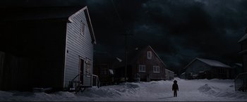 Movie still from “30 Days of Night” (2007), directed by David Slade – A person standing in front of a house on a snowy day; Extreme Wide shot, Low angle