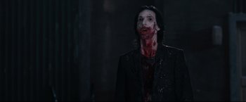 Movie still from “30 Days of Night” (2007), directed by David Slade – A man with blood on his face standing in a dark room; Medium shot, Over the shoulder angle