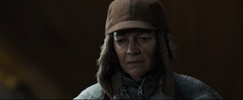 Movie still from “30 Days of Night” (2007), directed by David Slade – An older woman wearing a brown hat and a jacket; Close Up shot, Over the shoulder angle