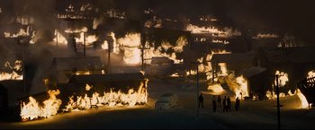 Movie still from “30 Days of Night” (2007), directed by David Slade – A group of people standing in front of a burning building; Extreme Wide shot, High angle