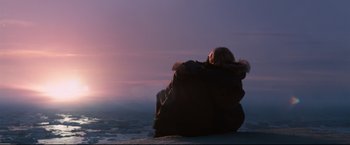 Movie still from “30 Days of Night” (2007), directed by David Slade – A woman sitting on a beach at sunset; Extreme Wide shot, Low angle