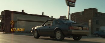 Movie still from “30 Minutes or Less” (2011), directed by Ruben Fleischer – A car driving down a street next to a building; Wide shot, Low angle