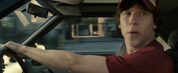 Movie still from “30 Minutes or Less” (2011), directed by Ruben Fleischer – A man driving a car in a red shirt; Close Up shot, Over the shoulder angle