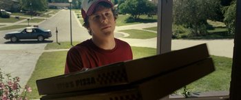 Movie still from “30 Minutes or Less” (2011), directed by Ruben Fleischer – A young man sitting in front of two pizza boxes; Medium shot, Over the shoulder angle