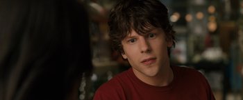 Movie still from “30 Minutes or Less” (2011), directed by Ruben Fleischer – A young man in a red t - shirt is looking at the camera; Close Up shot, Over the shoulder angle