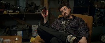 Movie still from “30 Minutes or Less” (2011), directed by Ruben Fleischer – A man sitting in a chair holding a nintendo wii controller; Medium shot, High angle