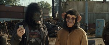 Movie still from “30 Minutes or Less” (2011), directed by Ruben Fleischer – Two people wearing gorilla masks in front of a pile of junk; Medium shot, Over the shoulder angle