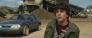 Movie still from “30 Minutes or Less” (2011), directed by Ruben Fleischer – A young man standing next to a car in a parking lot; Close Up shot, Over the shoulder angle