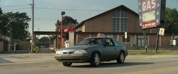 Movie still from “30 Minutes or Less” (2011), directed by Ruben Fleischer – An old car parked on the side of the street; Extreme Wide shot, Low angle