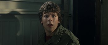 Movie still from “30 Minutes or Less” (2011), directed by Ruben Fleischer – A young man with curly brown hair wearing a green jacket; Close Up shot, Over the shoulder angle