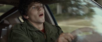 Movie still from “30 Minutes or Less” (2011), directed by Ruben Fleischer – A young man driving a car while holding a steering wheel; Close Up shot, Over the shoulder angle