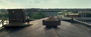 Movie still from “30 Minutes or Less” (2011), directed by Ruben Fleischer – A man standing on top of a building near a pile of dirt; Extreme Wide shot, Low angle