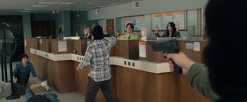 Movie still from “30 Minutes or Less” (2011), directed by Ruben Fleischer – A man in a plaid shirt is standing in front of a counter; Wide shot, Over the shoulder angle