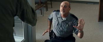 Movie still from “30 Minutes or Less” (2011), directed by Ruben Fleischer – A man in a police uniform is sitting on the floor; Medium shot, Over the shoulder angle