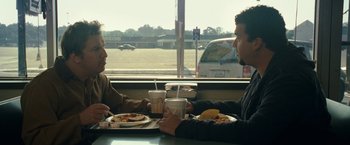 Movie still from “30 Minutes or Less” (2011), directed by Ruben Fleischer – Two men sitting at a table with plates of food; Medium shot, Over the shoulder angle
