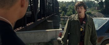 Movie still from “30 Minutes or Less” (2011), directed by Ruben Fleischer – A man standing next to a body of water; Medium shot, Over the shoulder angle