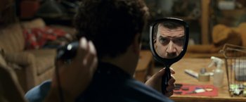 Movie still from “30 Minutes or Less” (2011), directed by Ruben Fleischer – A man looking into a mirror while brushing his hair; Close Up shot, Over the shoulder angle