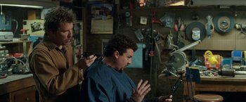 Movie still from “30 Minutes or Less” (2011), directed by Ruben Fleischer – A man getting his hair combed by another man; Medium shot, Over the shoulder angle