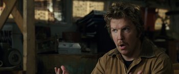 Movie still from “30 Minutes or Less” (2011), directed by Ruben Fleischer – A man with blue eyes and brown jacket talking to the camera; Close Up shot, Over the shoulder angle