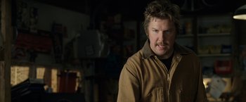 Movie still from “30 Minutes or Less” (2011), directed by Ruben Fleischer – A man in a brown jacket is standing in a room; Close Up shot, Over the shoulder angle