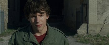 Movie still from “30 Minutes or Less” (2011), directed by Ruben Fleischer – A young man in a green jacket is looking to his left; Close Up shot, Over the shoulder angle