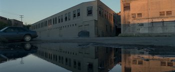 Movie still from “30 Minutes or Less” (2011), directed by Ruben Fleischer – A building that is reflected in a puddle; Extreme Wide shot, High angle