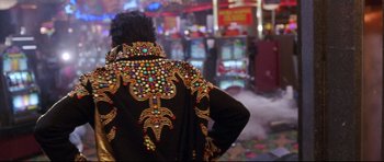 Movie still from “3000 Miles to Graceland” (2001), directed by Demian Lichtenstein – A man wearing a black jacket with colorful embellishments on it; Medium shot, Over the shoulder angle