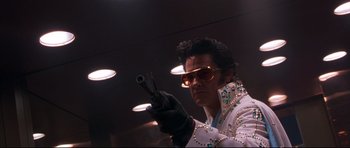 Movie still from “3000 Miles to Graceland” (2001), directed by Demian Lichtenstein – A man dressed as elvis presley holding a gun; Medium shot, Low angle