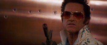 Movie still from “3000 Miles to Graceland” (2001), directed by Demian Lichtenstein – A person wearing sunglasses and holding a gun; Close Up shot, Low angle