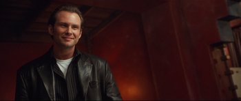 Movie still from “3000 Miles to Graceland” (2001), directed by Demian Lichtenstein – A man wearing a black leather jacket standing in front of a red wall; Close Up shot, Low angle