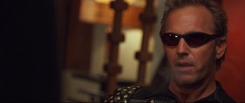 Movie still from “3000 Miles to Graceland” (2001), directed by Demian Lichtenstein – A man with sunglasses is sitting in front of a lamp; Close Up shot, Low angle