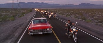 Movie still from “3000 Miles to Graceland” (2001), directed by Demian Lichtenstein – A group of people on motorcycles driving down a road; Wide shot, High angle