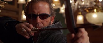 Movie still from “3000 Miles to Graceland” (2001), directed by Demian Lichtenstein – A person holding a bow and arrow; Close Up shot, Over the shoulder angle