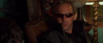 Movie still from “3000 Miles to Graceland” (2001), directed by Demian Lichtenstein – A man wearing sunglasses sitting in a chair; Close Up shot, Low angle