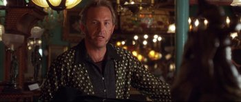 Movie still from “3000 Miles to Graceland” (2001), directed by Demian Lichtenstein – A person sitting in a room with lights in the background; Close Up shot, Over the shoulder angle