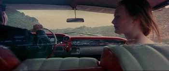 Movie still from “3000 Miles to Graceland” (2001), directed by Demian Lichtenstein – A woman sitting in the driver's seat of a red car; Medium shot, High angle