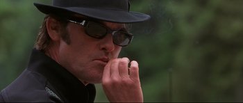 Movie still from “3000 Miles to Graceland” (2001), directed by Demian Lichtenstein – A man in a hat and sunglasses is smoking a cigarette; Close Up shot, Low angle