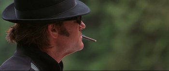 Movie still from “3000 Miles to Graceland” (2001), directed by Demian Lichtenstein – A person wearing a hat and smoking a cigarette; Close Up shot, Low angle