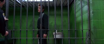 Movie still from “3000 Miles to Graceland” (2001), directed by Demian Lichtenstein – A man standing behind bars in a jail cell; Wide shot, Low angle